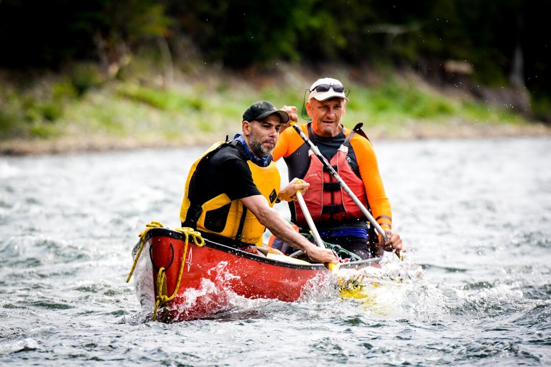 Colleagues paddling canoes together on a river during a team building outing